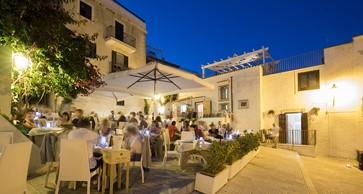 esterno con tavoli di legno del ristorante di pesce fresco centro storico di Vieste in piazzetta Petrone